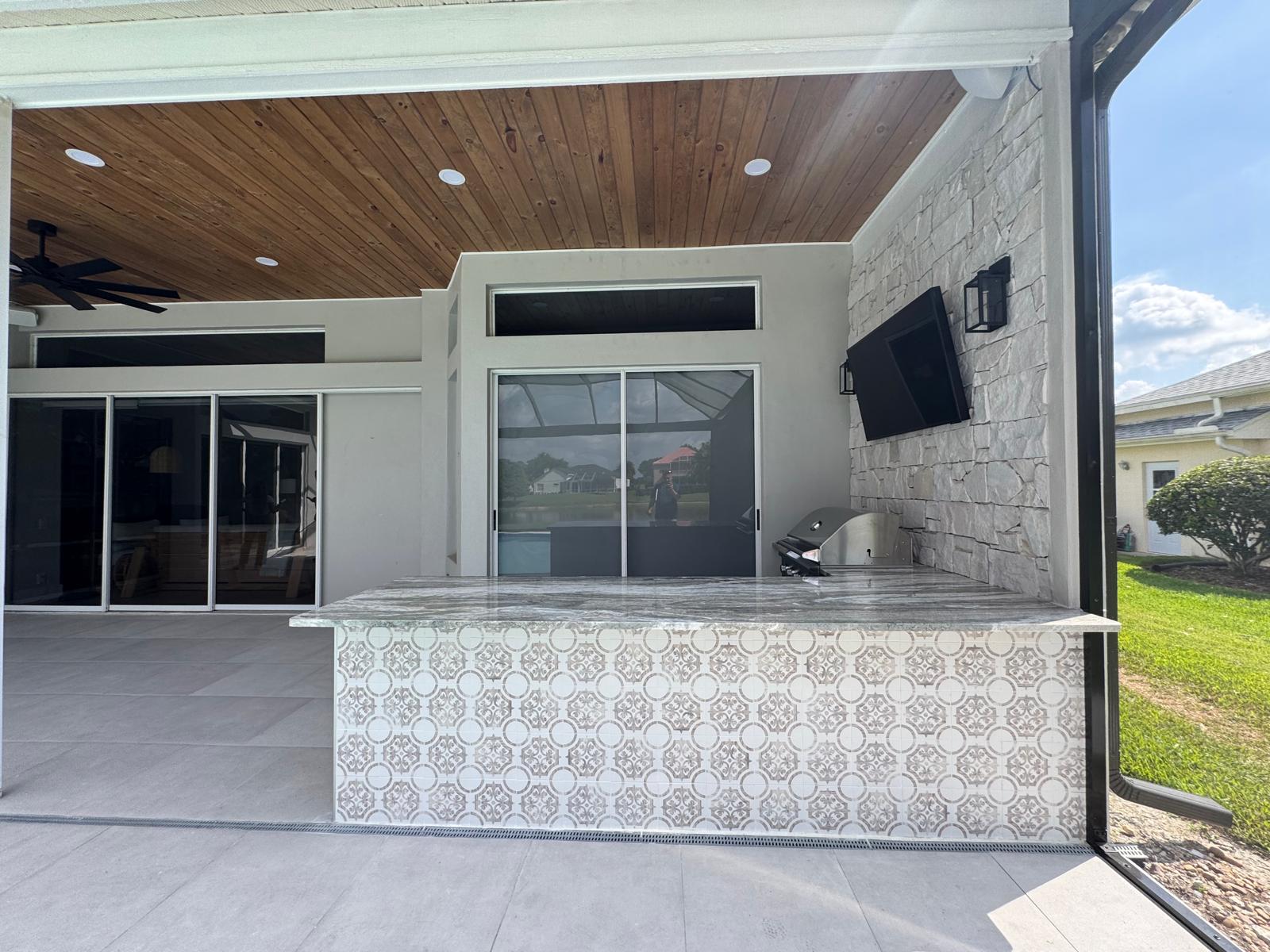 Covered outdoor kitchen with stone surfaces and a built-in grill
