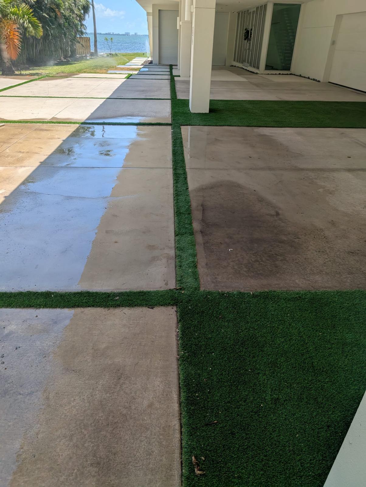 Patio paving with green turf strips beside a waterfront home